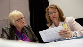 Alt text=” “Two women at a table, reviewing a document together 