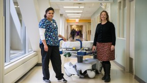 Esther Logan and Martha Witoe, standing next to a gurney in a hospital corridor. 