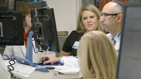 Doctors and nurses huddle around a computer