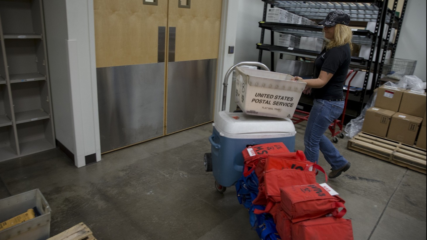 Courier with blue and red packages on a dolly 