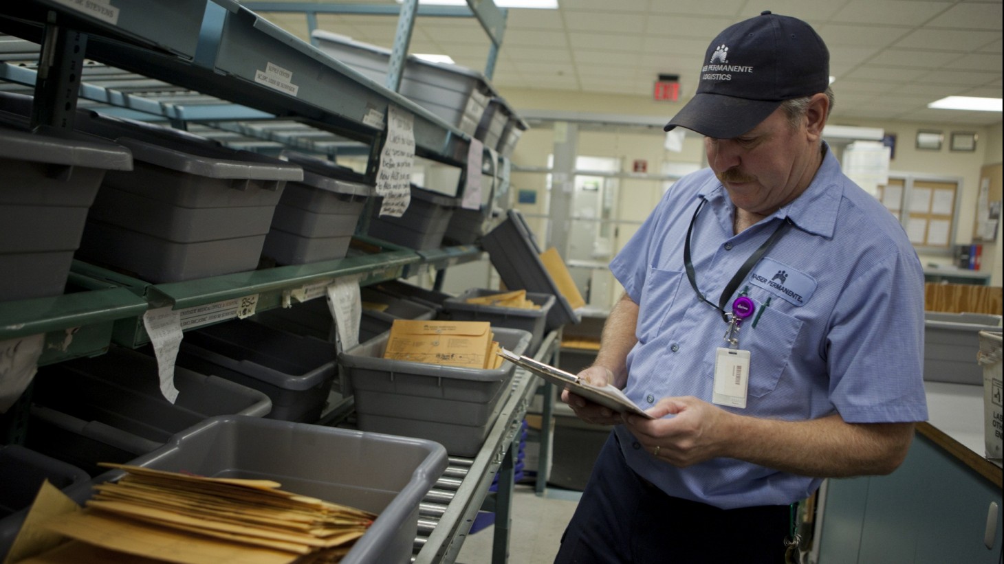 A courier looking at a package next to bins